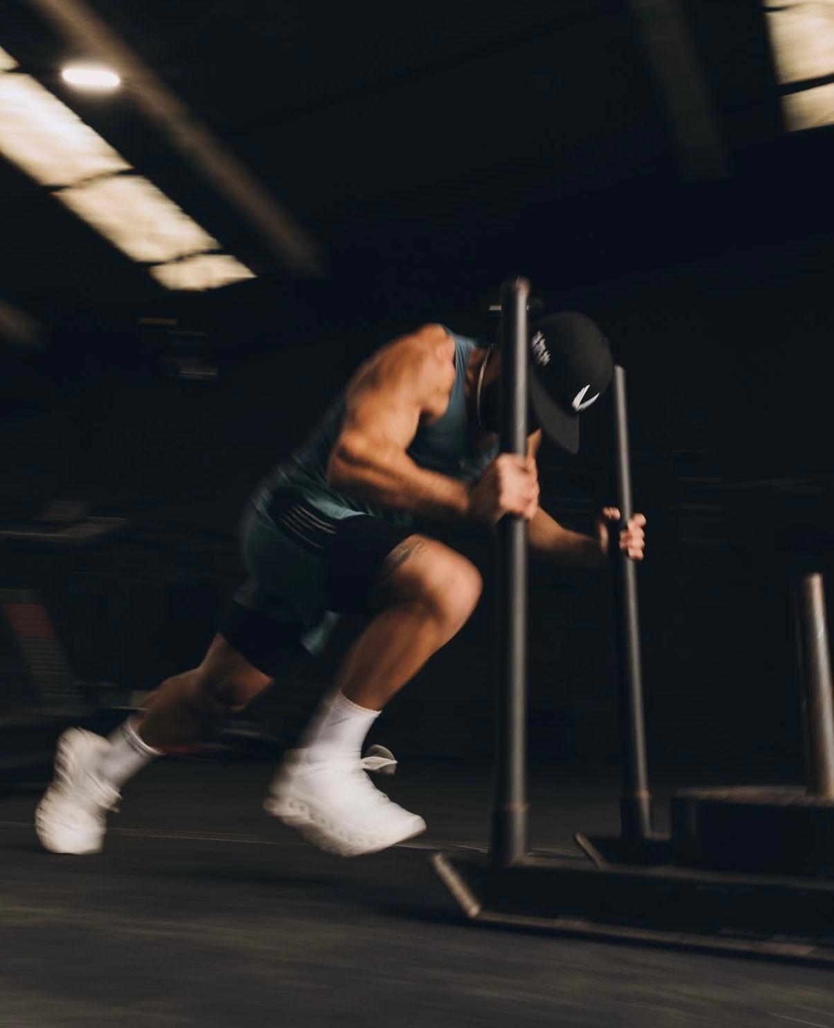 Athlete pushing a weighted sled across a training facility